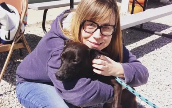 Woman in purple sweater hugging dog