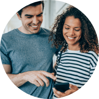 A person smiling while looking at a smartphone.